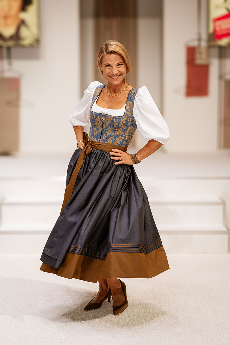 Kristina Sprenger im Dirndl bei der FESCH Salzburg – Dirndl Trends 2026 mit blau-goldenem Mieder und modernem Trachtenlook