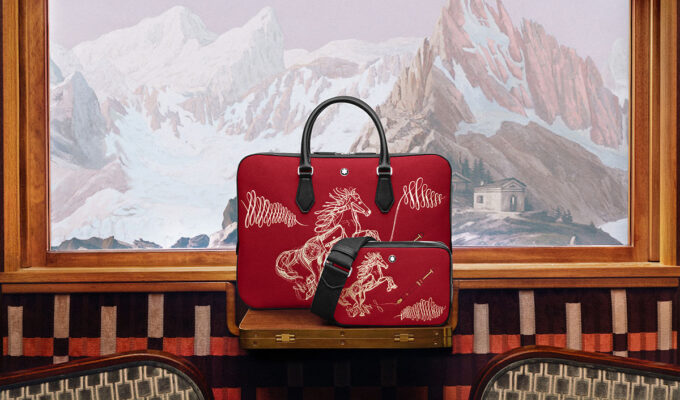 Rote Lederhandtasche und Crossbody-Bag von Montblanc mit goldener Pferdeillustration vor alpiner Bergkulisse im Jahr des Feuer-Pferdes 2026.