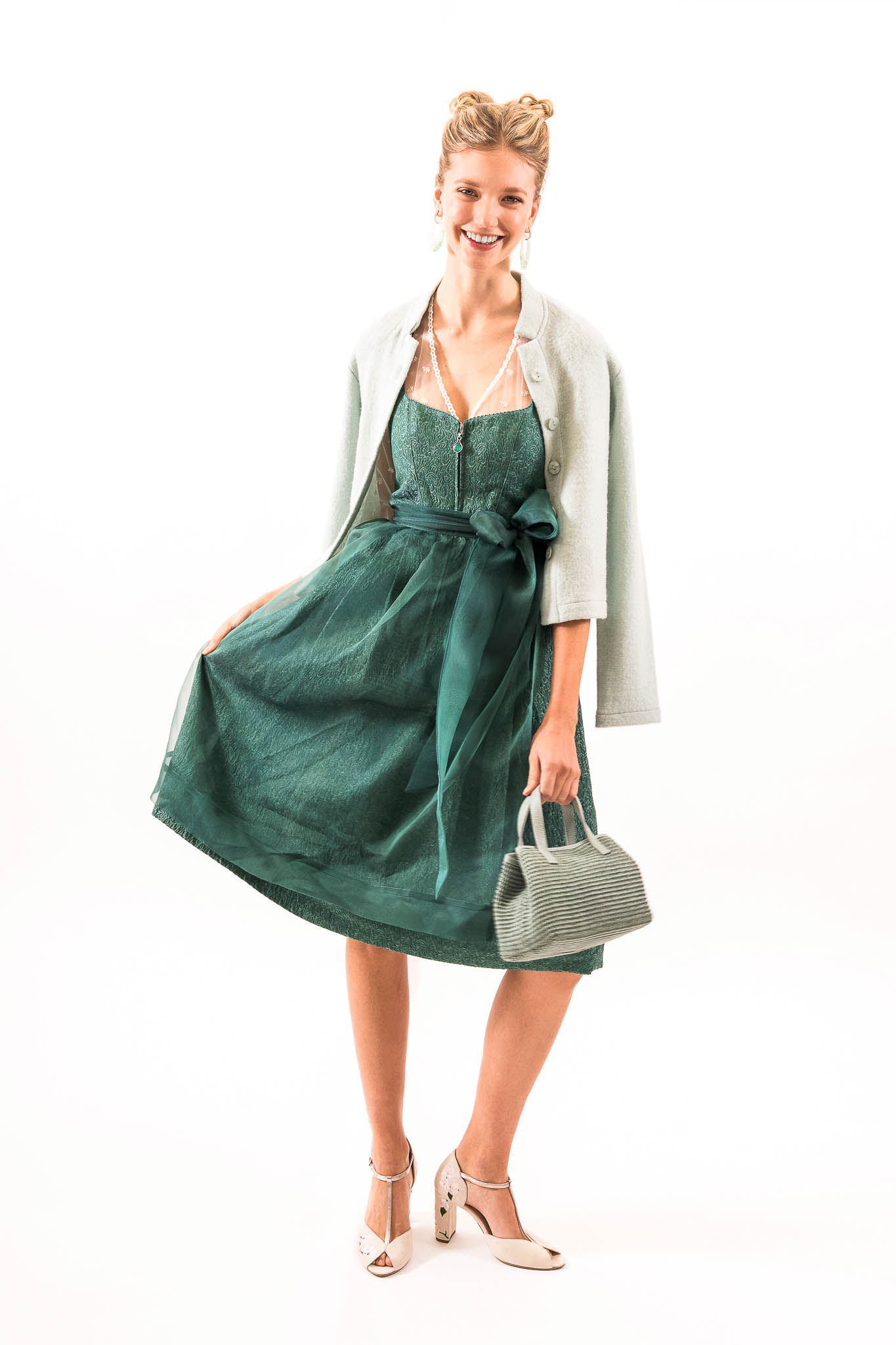 Modernes Dirndl mit Strickjacke Modernes grünes Dirndl mit leichter Strickjacke und Tasche – Tracht Trends Frühjahr Sommer 2026.