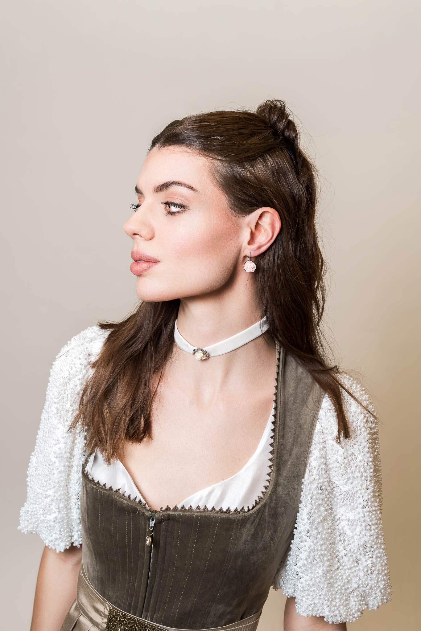 Dirndl mit Spitzenbluse und modernem Kropfband Dirndl mit Spitzenbluse, Kropfband und Ohrringen – Tracht Trends Frühjahr Sommer 2026.