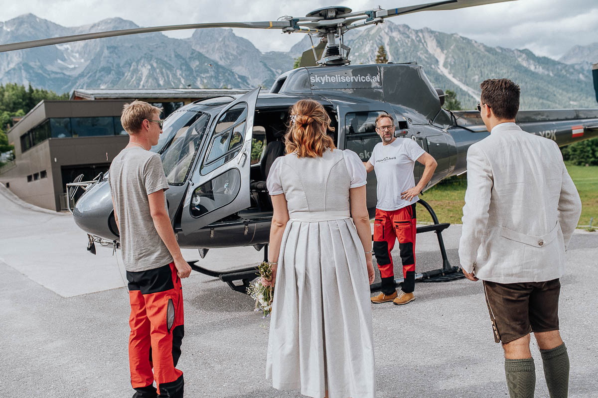 Brautpaar steht vor einem Helikopter bereit für den Flug in die Berge