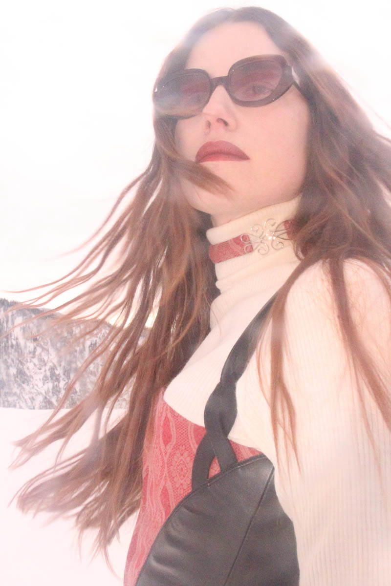 Frau mit Sonnenbrille und Choker von MARIAHAUSE vor verschneiter Berglandschaft