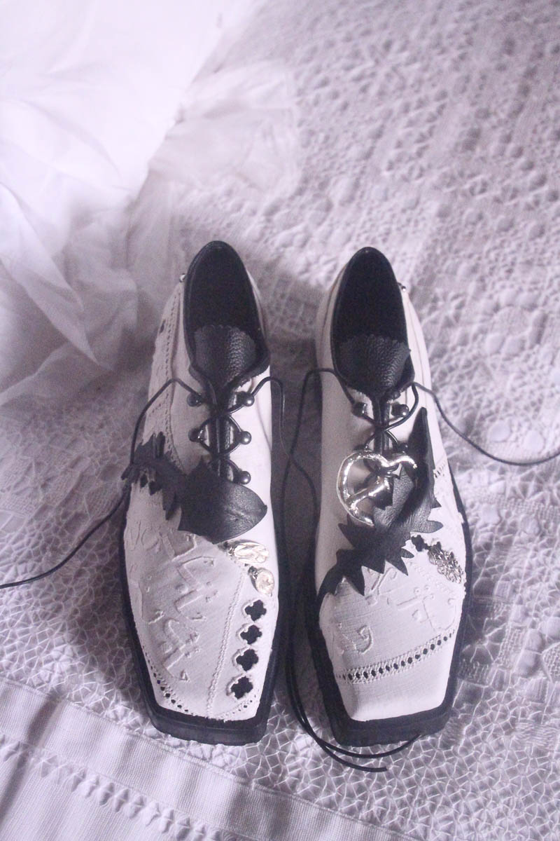 Paar handgefertigter weißer Lederschuhe von MARIAHAUSE mit applizierten Details auf Stoff