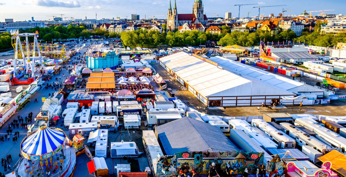 Münchner Frühlingsfest 2026 auf der Theresienwiese mit Fahrgeschäften, Bierzelten und Blick über München. © fottoo - stock.adobe.com