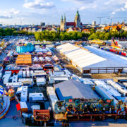 Münchner Frühlingsfest 2026 auf der Theresienwiese mit Fahrgeschäften, Bierzelten und Blick über München. © fottoo - stock.adobe.com