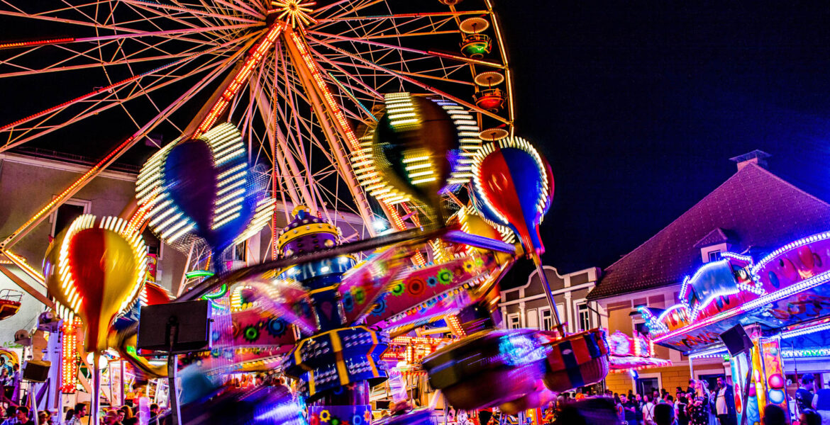 Fahrgeschäfte auf dem Villacher Kirchtag bei Nacht mit bunten Lichtern. Foto: AdobeStock/ANDREAS