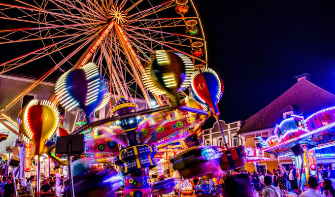 Fahrgeschäfte auf dem Villacher Kirchtag bei Nacht mit bunten Lichtern. Foto: AdobeStock/ANDREAS