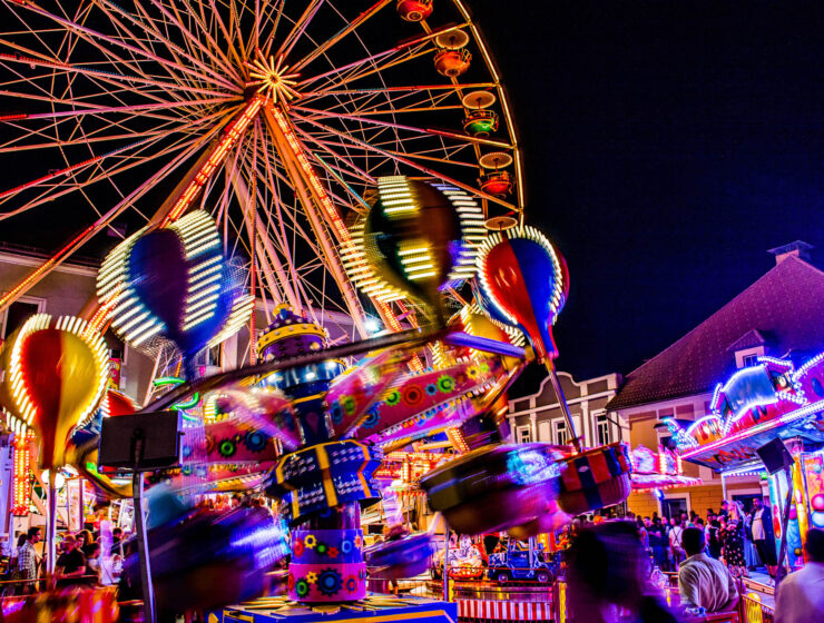 Fahrgeschäfte auf dem Villacher Kirchtag bei Nacht mit bunten Lichtern. Foto: AdobeStock/ANDREAS