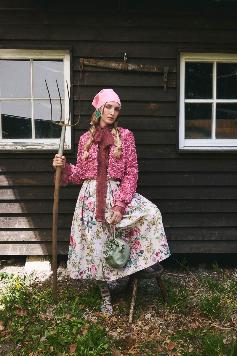 Landhaus-Romantik neu interpretiert Model in floraler Tracht vor rustikalem Holzhaus