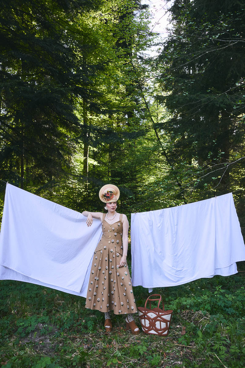Alpine Cottagecore-Ästhetik Model in floralem Kleid vor Wäscheleine im Wald
