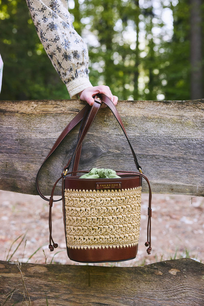 Naturmaterialien in der Trachtenmode Geflochtene Handtasche im Cottagecore-Stil an Holzzaun