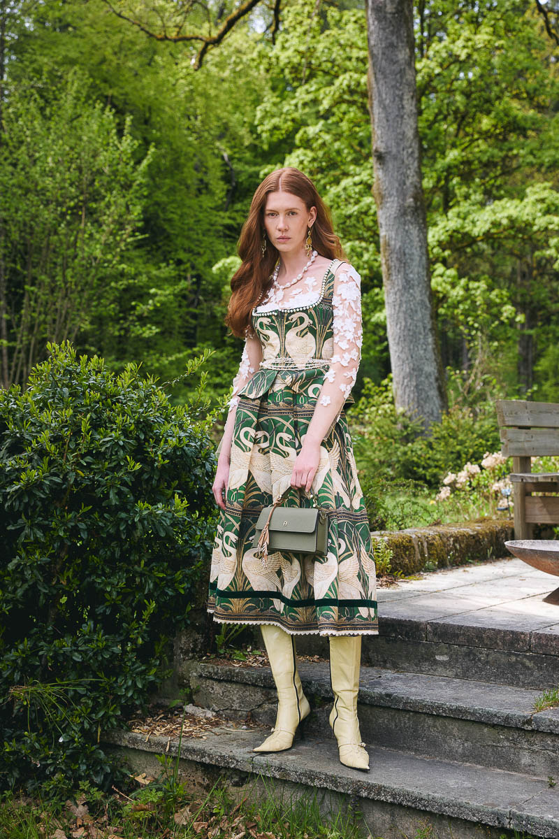 Moderne Tracht mit Art-déco-Flair Model in grün gemustertem Dirndl mit transparenter Spitzenbluse