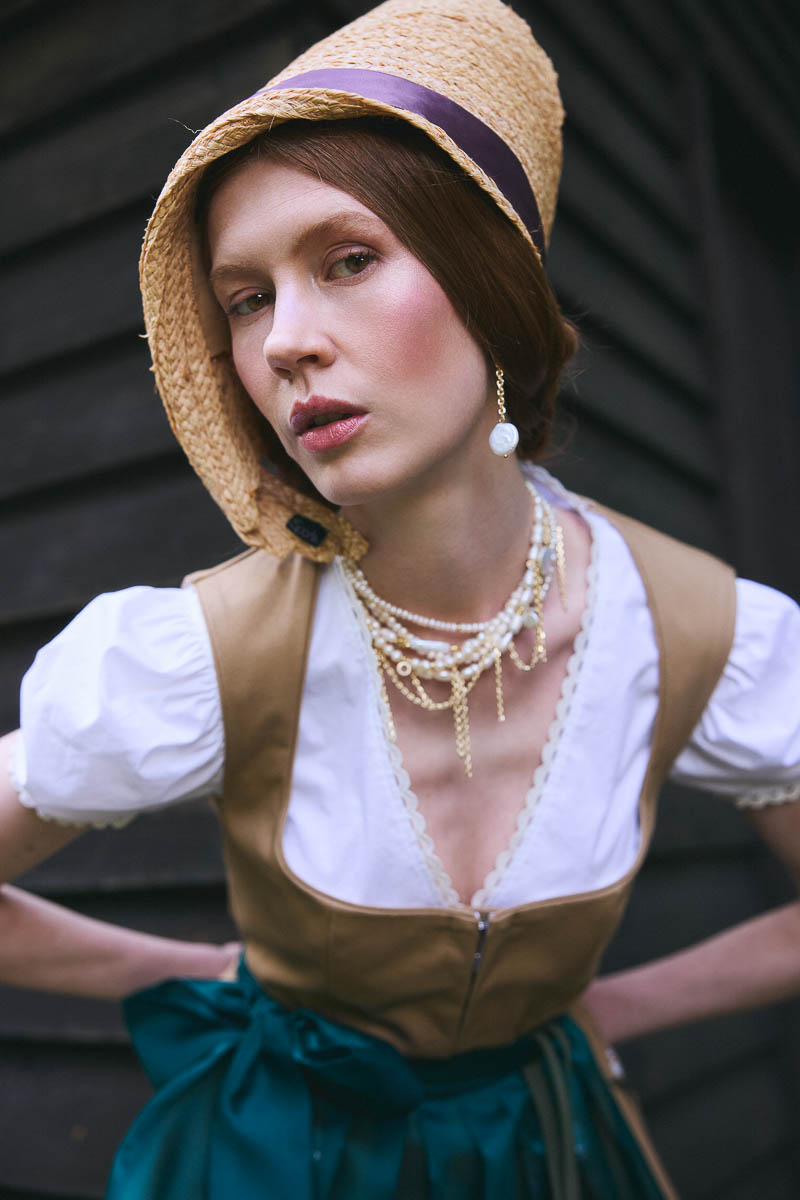 Alpine Couture-Portraits Portrait eines Models mit Strohhut und modernem Dirndl