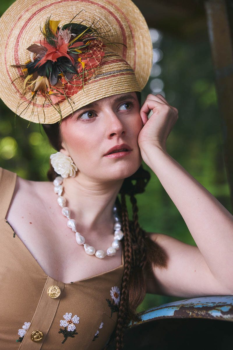Couture-Accessoires mit Nostalgie Detailaufnahme eines Strohhuts mit Perlenkette im Cottagecore-Stil