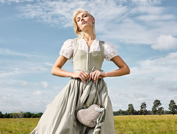 Modernes grünes Dirndl in Salbei von CocoVero aus der Frühjahr/Sommer-Kollektion 2026 auf einer sommerlichen Wiese fotografiert