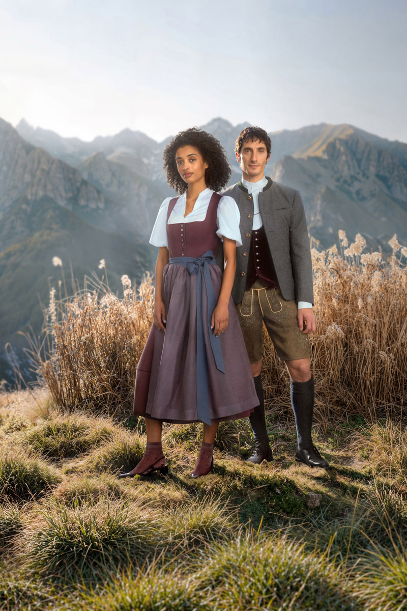 Frau im Dirndl und Mann in Lederhose in alpiner Landschaft