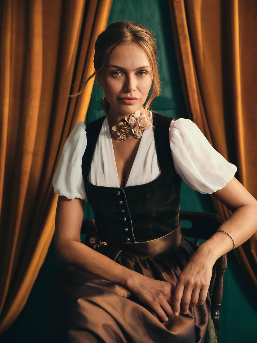 Dirndl Olivia und Bluse Robina von Amsel Frau im Dirndl mit bronzefarbener Schürze und weißer Bluse