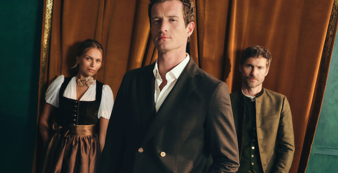 Drei Models in moderner Tracht von HIRMER, im Vordergrund ein Mann im dunklen Trachtenanzug