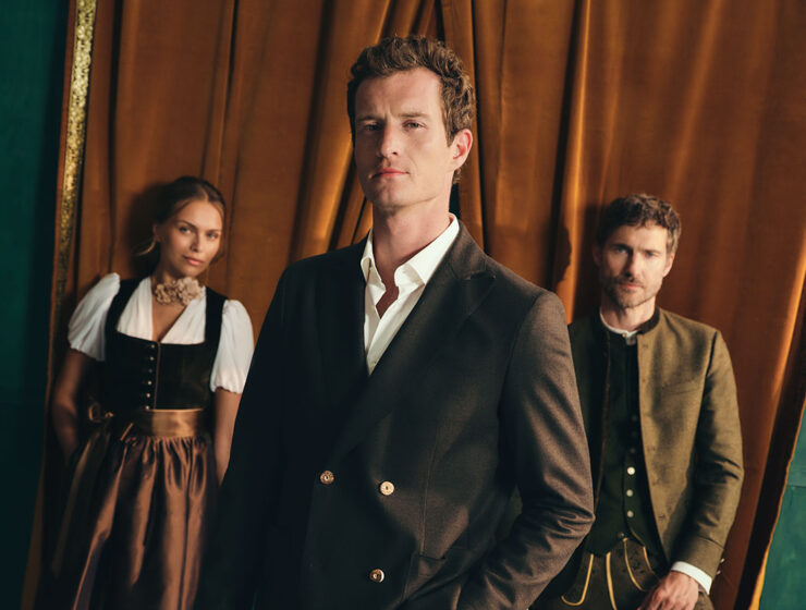 Drei Models in moderner Tracht von HIRMER, im Vordergrund ein Mann im dunklen Trachtenanzug