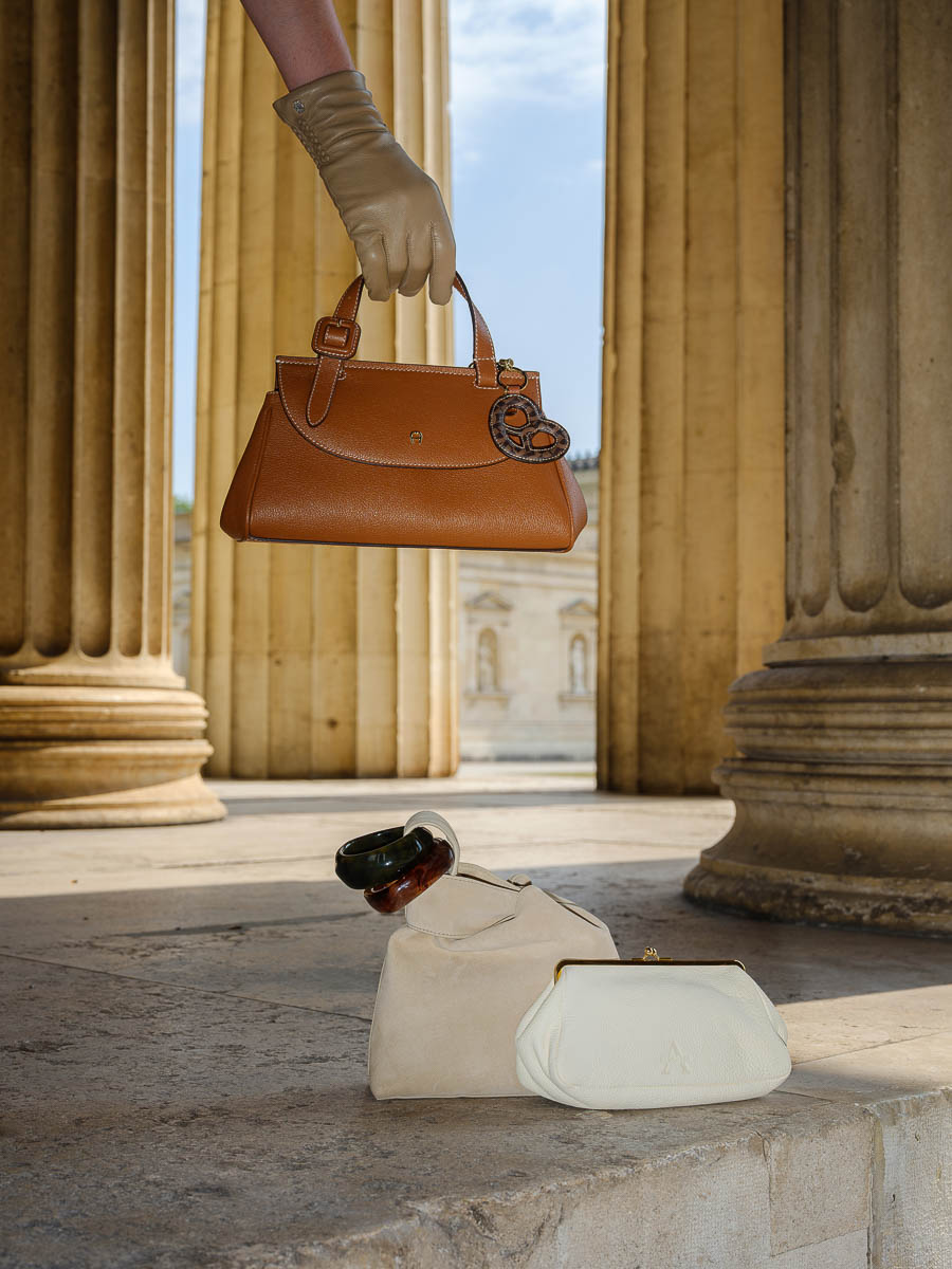 Braune und helle Handtaschen mit Lederhandschuhen vor den Säulen am Königsplatz in München